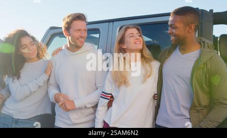 Group Of Young Friends On Road Trip Standing Next To Convertible Car Stock Photo