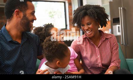 Smiling Family Relaxing And Laughing On Sofa At Home Together Stock Photo