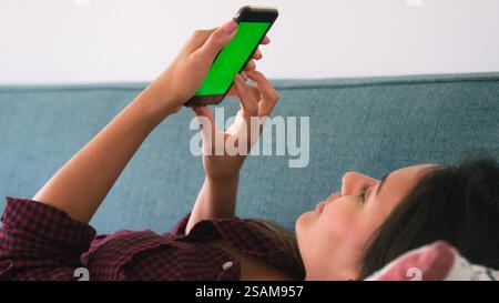 Close Up Of Woman Lying On Sofa At Home Using Green Screen Mobile Phone Stock Photo