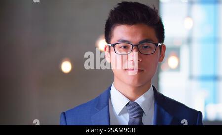 Portrait Of Confident Young Businessman Wearing Glasses Standing By Window In Office Stock Photo