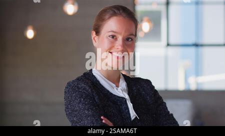 Head And Shoulders Portrait Of Smiling Confident Businesswoman Standing By Window In Modern Office Stock Photo