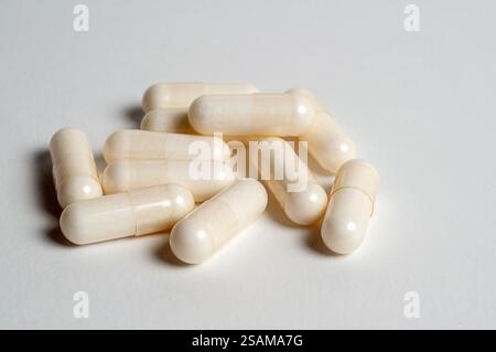 Pile of white capsules on a clean, white surface, symbolizing vitamins or supplements. Stock Photo
