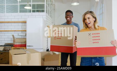 Smiling Young Couple Carrying Packing Boxes Moving Into New Home Stock Photo