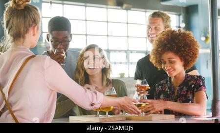 Female Server With Group Of Young Friends At Beer Tasting In Bar Stock Photo