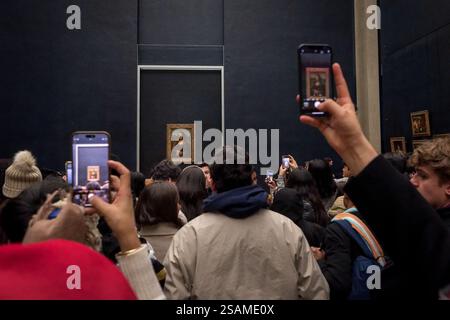 A crowd gathering at the Louvre, capturing the Mona Lisa through their smartphone screens, Paris, France - January 13, 2025 Stock Photo