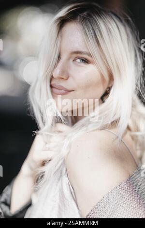 Close-up of a smiling woman outdoors with loose hair in sunlight Stock Photo