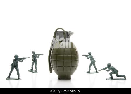 Several toy soldiers surrounding a hand grenade Stock Photo