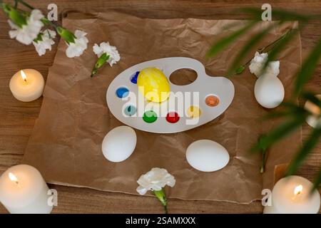 Creative Easter egg decorating activity with candles and flowers in spring setting Stock Photo