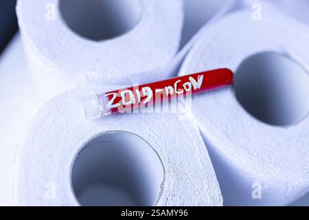 Red test tube labeled 2019-nCoV on stacked toilet paper rolls Stock Photo