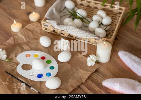 Creative Easter egg decorating activity with candles and flowers in spring setting Stock Photo