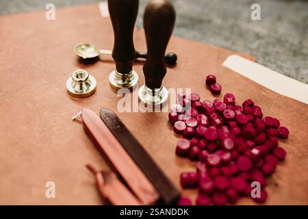 Sealing tools with red wax pellets and brown papers on table Stock Photo