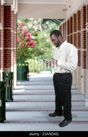 Black African American business man using a cell phone for texting Stock Photo