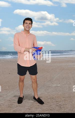 Handsome young man holding a sand pail and a toy shovel Stock Photo