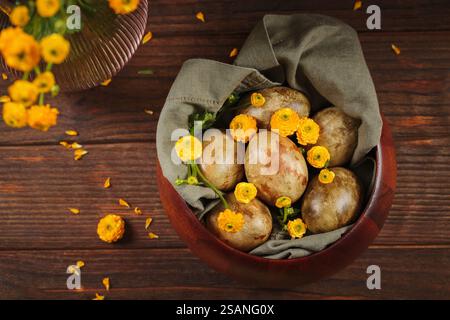 Top-down view of Easter eggs and yellow flowers in a wooden bowl Stock Photo