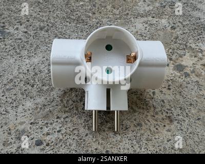 Close up of white electrical power plug adaptor cross to three sockets Stock Photo