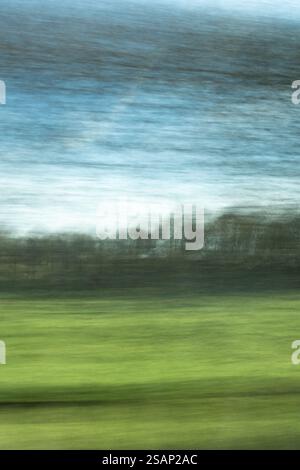 Driving through countryside in winter concept - blurred trees seen through window and fields beyond - uk Stock Photo