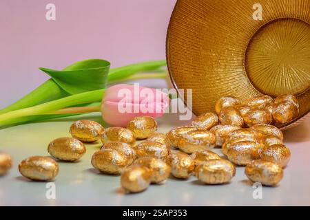 Gold foiled Easter eggs and pink tulips, close up; Happy Easter, Easter celebration, Spring celebration. Stock Photo