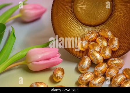 Gold foiled Easter eggs and pink tulips, close up; Happy Easter, Easter celebration, Spring celebration. Stock Photo