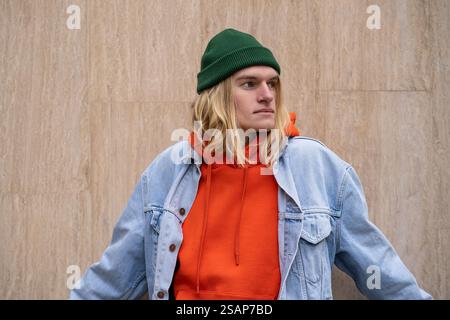 Portrait of stylish blond guy in trendy colorful outfit looking aside, thinking positive Stock Photo