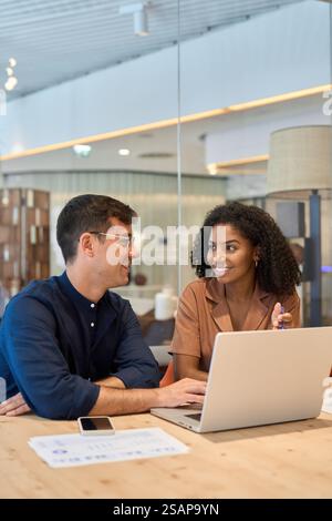 Young busy diverse colleagues business team using laptop in office. Vertical. Stock Photo