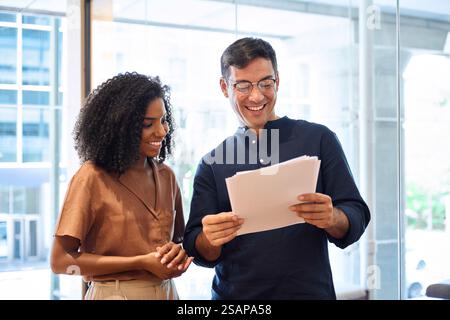 Busy business man and business woman standing in office talking about documents. Stock Photo