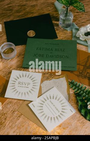 A beautifully arranged wedding invitation suite rests on a wooden table, featuring intricate designs, escort cards, and a decorative floral touch, cre Stock Photo