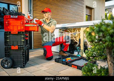 A technician focuses on repairing a hot tub outside a home. Tools are organized for efficient work, highlighting the repair activity in the bright env Stock Photo