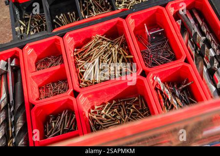 Various screws and drill bits are neatly arranged in compartments of a red toolbox, ideal for home improvement or construction projects. Stock Photo