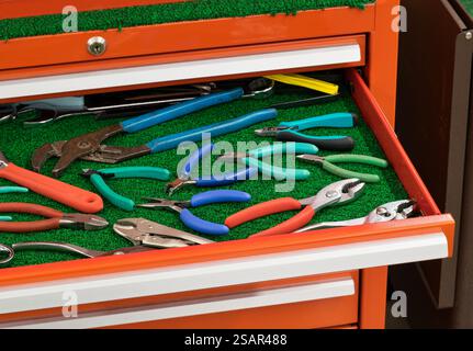 Assorted pliers wrench clamping tools displayed in open toolbox drawer. Stock Photo