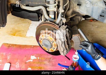 Mechanic working on replacing brake pads on vehicle. Stock Photo