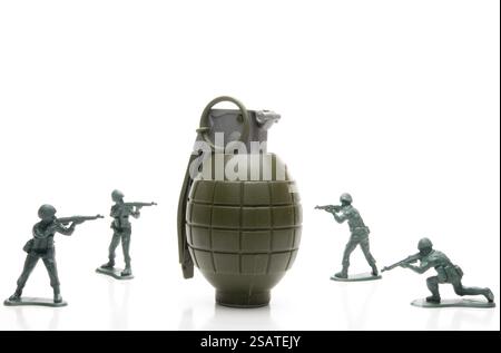 Several toy soldiers surrounding a hand grenade Stock Photo