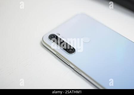 Close-up of a silver smartphone with quad cameras on a white surface Stock Photo