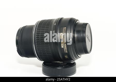 Daejeon, South Korea, Jan. 5, 2025: Closeup side view Nikkor 18-55mm camera lens resting on lens cap against white background, Asia Stock Photo