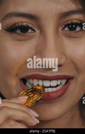 Woman biting the Electonic Currency known as Bitcoin Stock Photo