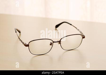eye glasses on a wooden table by the bright window Stock Photo