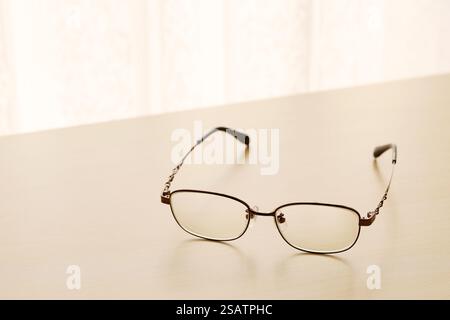 eye glasses on a wooden table by the bright window Stock Photo