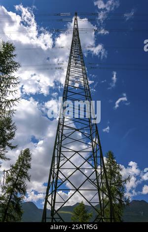 Low Angle View on Electricity Pylon with Tree and Mountain and Blue Sky and Clouds in a Sunny Summer Day in Engadine, Maloja, St moritz, Grisons, Swit Stock Photo