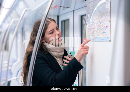 Young Woman Checking Subway Map While Using Smartphone Stock Photo