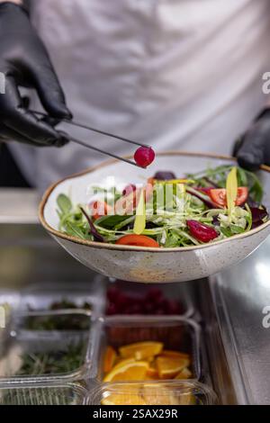 Chef adding final touches to fresh colorful salad in restaurant kitchen Stock Photo