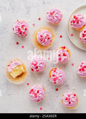Small cupackes with pink frosting and hearts on white background. Stock Photo