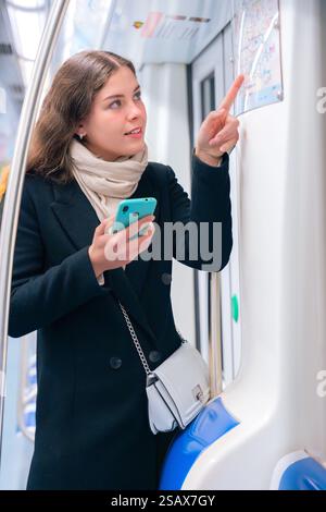 Young Woman Checking Subway Map While Using Smartphone.Vertical Stock Photo