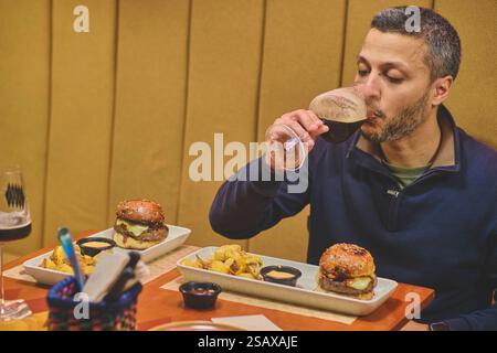 Young man enjoying a tasty beer and burger in craft beer bar Stock Photo