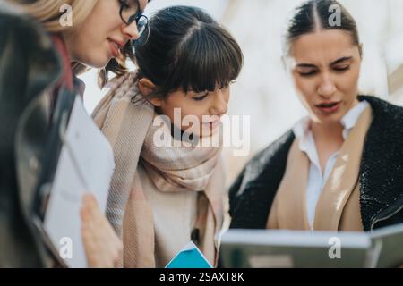 Three professional women collaborating outdoors and discussing documents Stock Photo