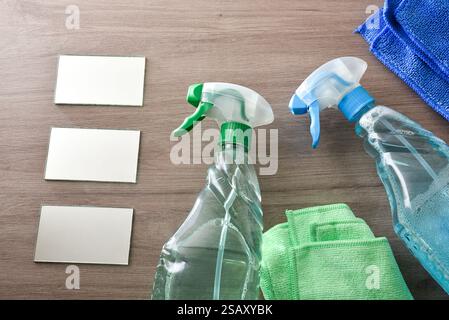 Cleaning products for dirt and dust in a transparent plastic bottle spray on wooden table with microfibre cloths and glass. Top view. Stock Photo