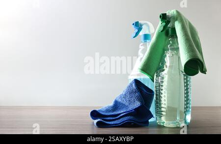 Spray bottles with general household cleaning product with microfiber cloths on wooden table and white isolated background. Front view. Stock Photo