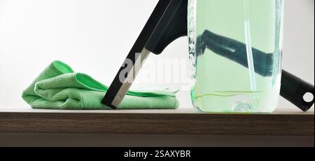 Window cleaner spatula, spray product and microfibre cloth on wooden table white isolated background. Front view. Stock Photo