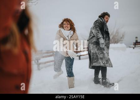 Group enjoying a lively snowball fight in a snowy winter setting Stock Photo