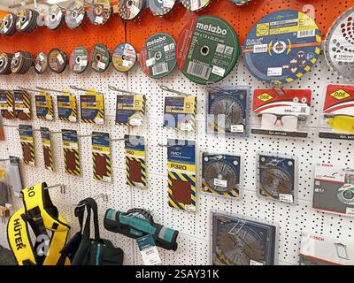 Variety of circular saw blades and sanding discs displayed on pegboard in hardware store. Stock Photo