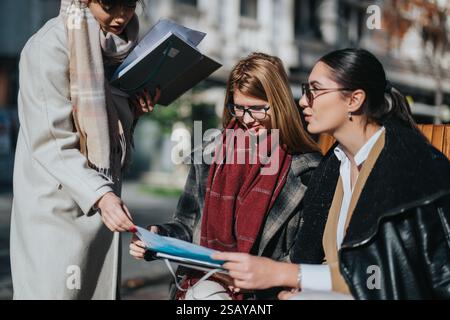 Three businesswomen collaborating outdoors with documents and ideas Stock Photo