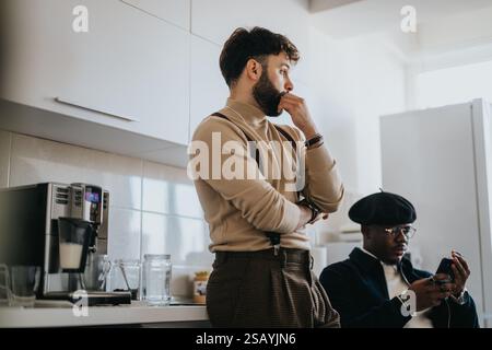 Two young professionals in a modern office kitchen discussing and using technology Stock Photo